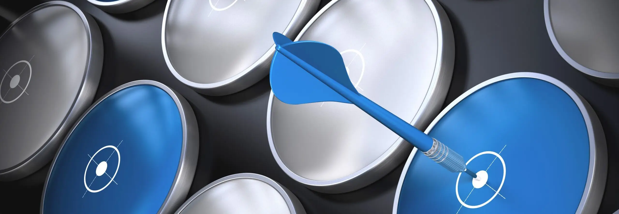 A close-up of a grid of glossy blue and silver dartboard-like discs on a dark background, with a single blue dart striking the bullseye of one blue disc.